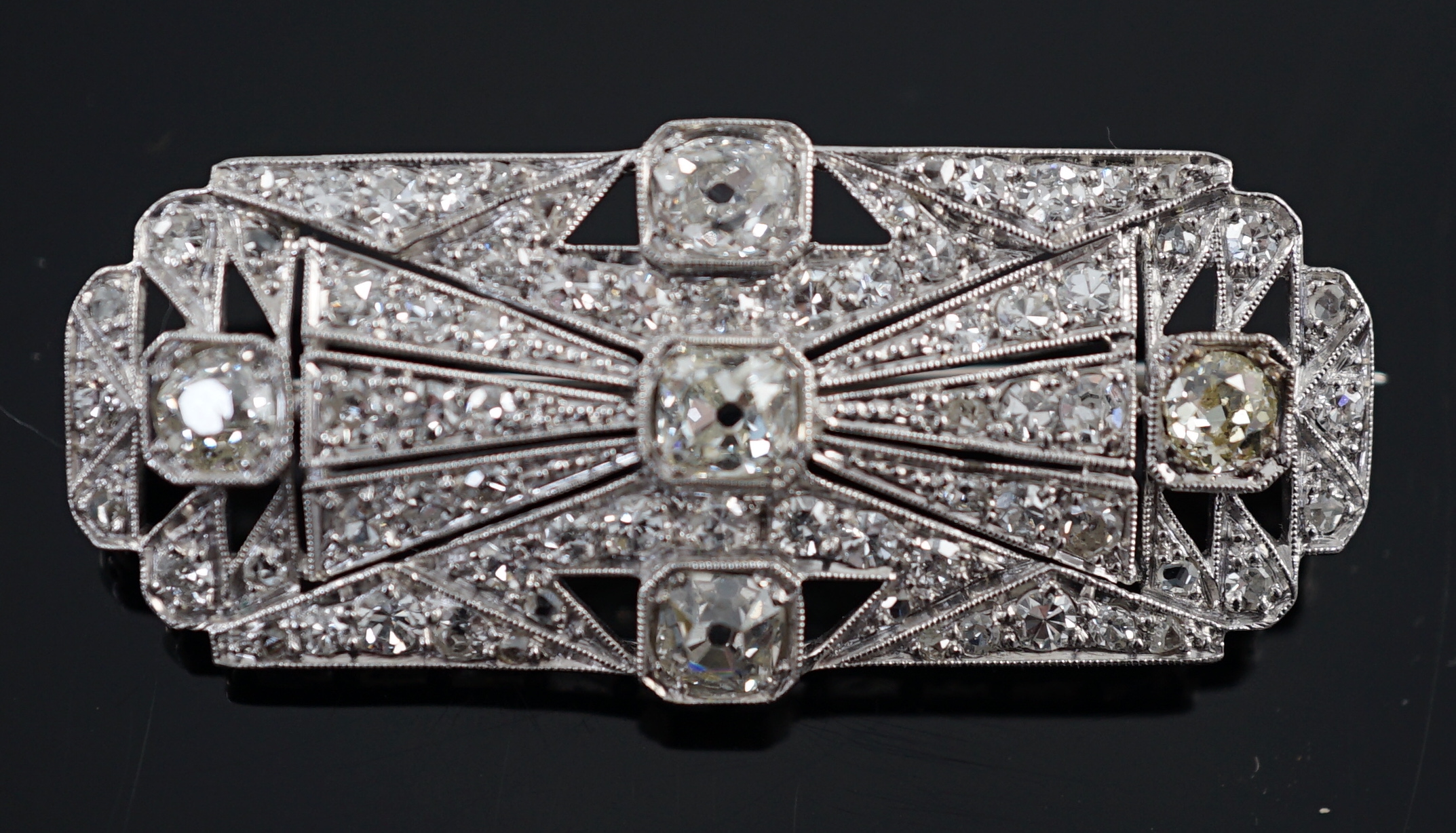 An Art Deco pierced platinum and millegrain set diamond cluster shaped rectangular brooch